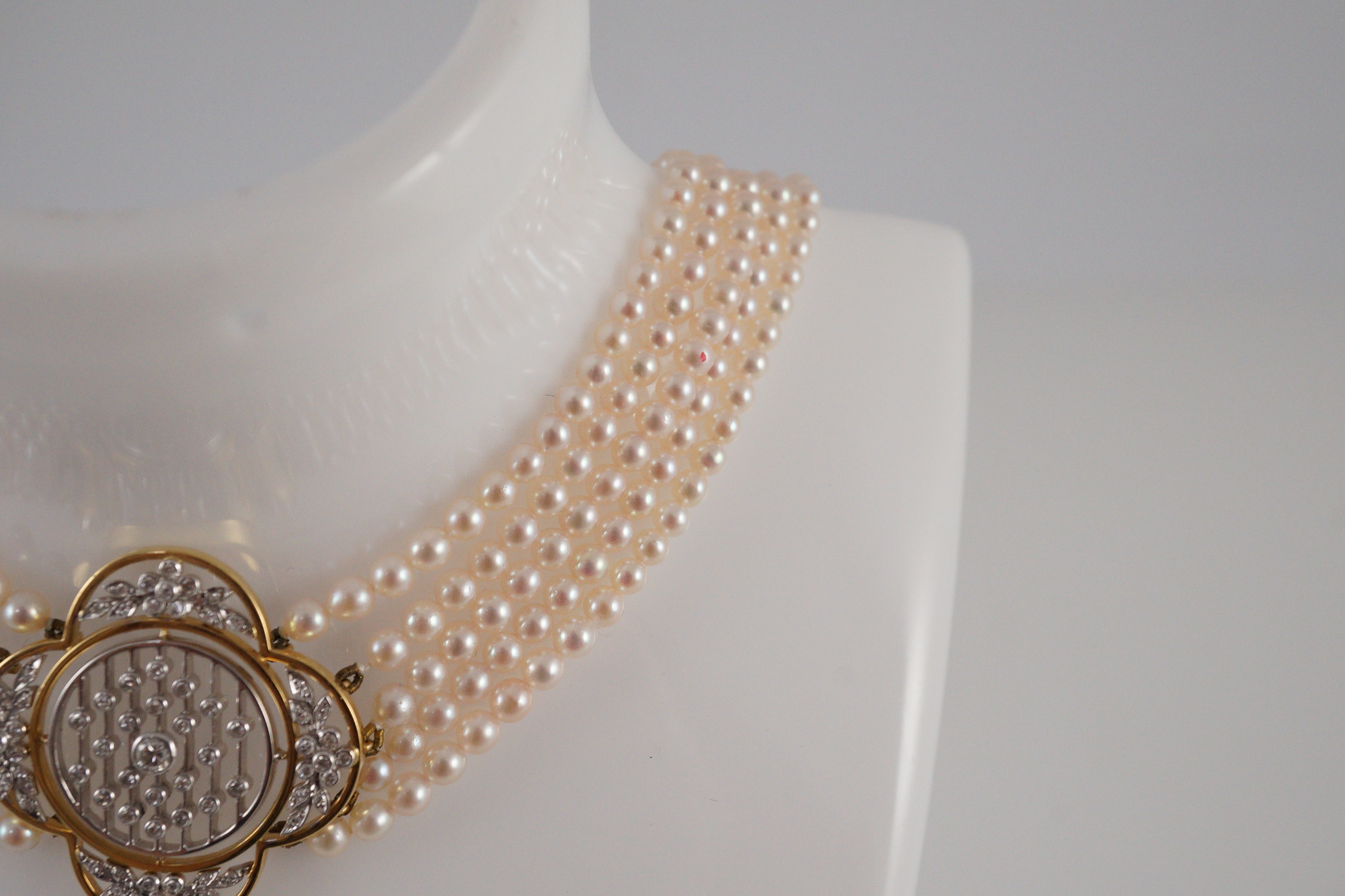 A quintuple strand seed pearl choker necklace, with pierced gold, platinum and diamond cluster set quatrefoil shaped clasp